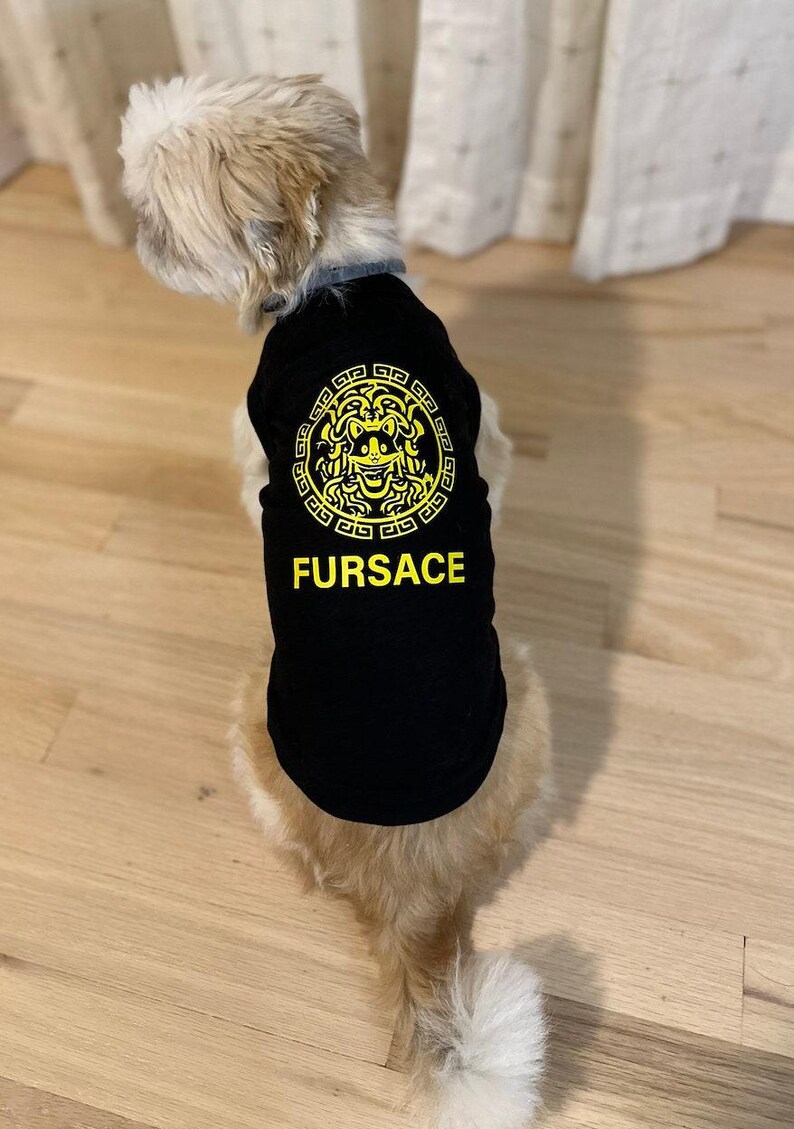 Black Dog shirt with the word FURSACE printed on it in yellow. The face in the logo is of a dog, incorporating dog ears and a smiling expression. The T-Shirt is designed for dogs, playing on the designer fashion brand in a humorous way.