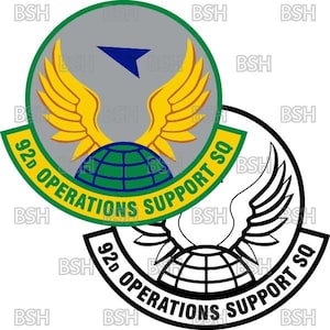 Op de afbeelding: Een cirkelvormig embleem met een grijze achtergrond, een blauwe driehoek en gele vleugels. Onder de vleugels bevindt zich een groene en blauwe wereldbol. Het embleem is omgeven door een groene rand met de tekst "92d OPERATIONS SUPPORT SQ". Er is ook een zwart-wit versie.