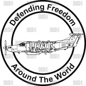 Può includere: Un grafico circolare in bianco e nero che presenta il profilo laterale di un aereo turboelica al centro. Il testo 'Defending Freedom' è arcuato nella parte superiore e 'Around The World' in quella inferiore. Il numero '100K' è centrato.