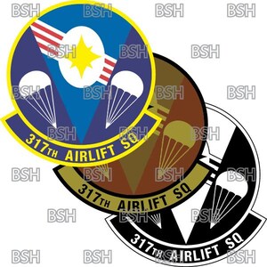Peut inclure: Trois versions d'un écusson d'unité militaire. Le premier écusson est bleu, jaune et rouge avec une étoile et trois parachutes. Le deuxième écusson est marron, jaune et blanc avec un parachute. Le troisième écusson est noir, blanc et gris avec un parachute. Les trois écussons portent le texte "317th Airlift SQ".