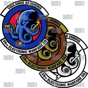 以下が含まれることがあります： 白い輪郭を持つ3つの重なり合った円形のワッペン。一番上のワッペンは、赤い中心と鍵を持ったスタイリッシュなタコが描かれた青色です。一番上のワッペンには「VIGILAMUS AB UMBRIS」というテキストが書かれています。真ん中のワッペンは、金色の中心とスタイリッシュな稲妻が描かれた茶色です。一番下のワッペンは、黒い中心とスタイリッシュな稲妻が描かれた白です。3つのワッペンすべてに「39th ELECTRONIC WARFARE SQ」というテキストが書かれています。