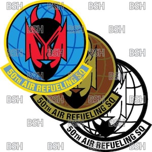 Op de afbeelding: Drie ronde patches met de tekst "50th Air Refueling SQ" en een grafisch ontwerp van een rood duivelshoofd, een man met een bruine baard en een zwart-witte wereld.