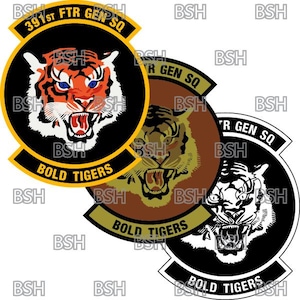 Könnte beinhalten: Drei schwarze, braune und weiße Patches mit einem Tigerkopf-Design. Jeder Patch hat den Text "391st FTR GEN SQ" und "BOLD TIGERS" in Gelb.