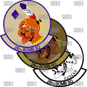 May include: A circular patch with a tan background and a blue diamond in the top left corner. The patch features a Native American profile with a red and yellow headdress and a feather. The text "28th BOMB SQ" is written in a blue arc around the bottom of the patch.