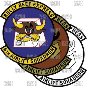 Może przedstawiać: Okrągła naszywka w kolorze niebieskim i żółtym z napisem "Bully Beef Express 6th Airlift Squadron" i kreskówkowym bykiem z czerwonym nosem i żółtymi rogami. Byk znajduje się wewnątrz białego kwadratu na niebieskim tle.