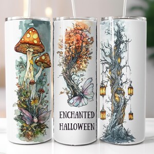 May include: Three white insulated tumblers with fantasy-themed illustrations. One features mushrooms, another a tree with a butterfly, and the third a tree with lanterns. The middle tumbler has the text "ENCHANTED HALLOWEEN".