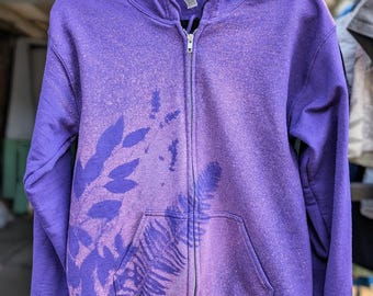 Sudadera con capucha y cremallera color morado teñida con lejía, inspirada en la naturaleza, con estampado de helechos y hojas.