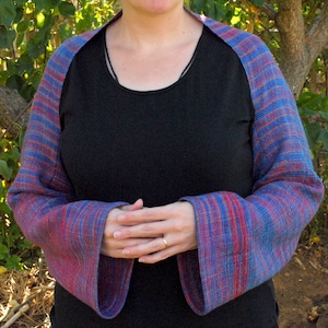 May include: A blue and red striped shawl with a black long-sleeved shirt underneath.