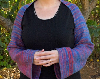 May include: A blue and red striped shawl with a black long-sleeved shirt underneath.