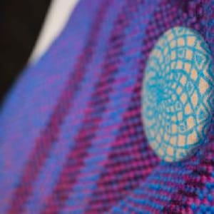 Puede incluir: Primer plano de una tela tejida azul y morada con un círculo estampado blanco y azul en el centro.