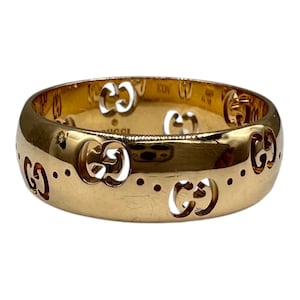 May include: A gold-colored ring with cut-out interlocking G logos and small dotted accents. The ring has a polished, reflective surface. The word "ICON" is visible on the inside of the ring.