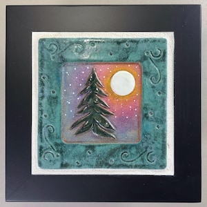 May include: A ceramic tile with a green border and a white background. The tile features a stylized image of a pine tree with a full moon in the background. The sky is a gradient of pink, purple, and blue with white dots.