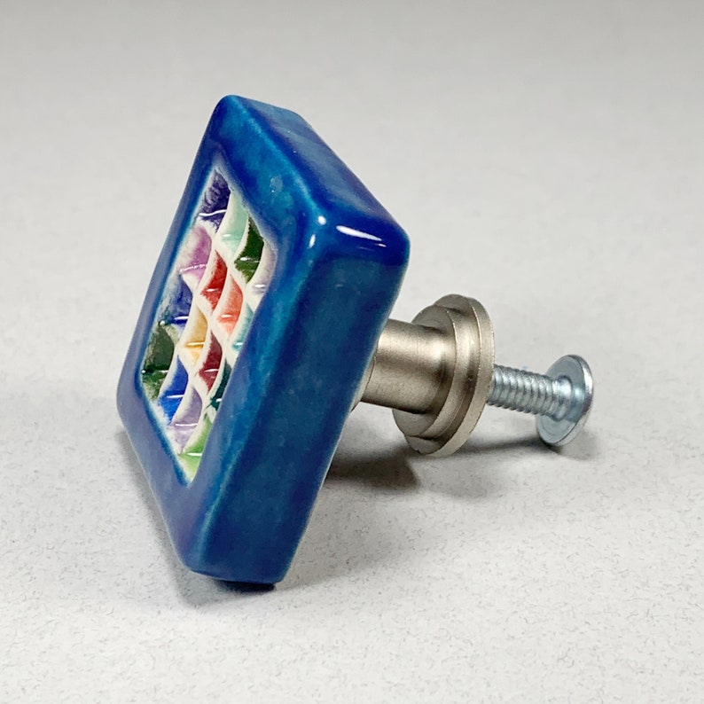 Puede incluir: Pomo cuadrado de cer&aacute;mica para armario con un dise&ntilde;o de mosaico colorido en un esmalte azul. El pomo tiene un tornillo de montaje de metal plateado.