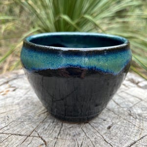 Handmade pottery bowl, black glaze with blue/green accent.