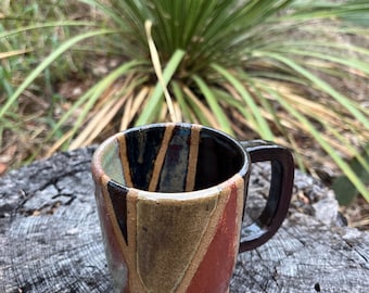 Handmade pottery 10 ounce mug with multicolored earth toned geometric patterned glaze.