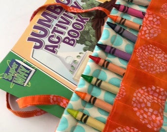 May include: A colorful crayon roll with a Super Why Jumbo Activity Book. The roll is orange with a floral pattern and holds various crayons. The activity book has a green cover with the title "Jumbo Activity Book".