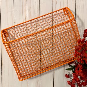 K&ouml;nnte beinhalten: Orangefarbener Wandkorb aus Metalldraht. Der Korb ist rechteckig und hat ein Gittermuster.