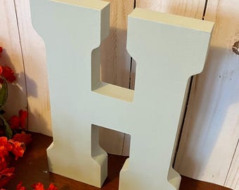 May include: A large, light green wooden letter H. The letter is freestanding and has a slightly distressed finish.