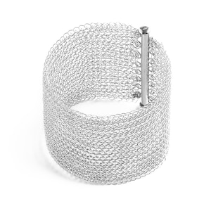 Puede incluir: Un brazalete de malla plateada con un cierre simple. El brazalete est&aacute; hecho de una malla fina y delicada, flexible y c&oacute;moda de llevar.