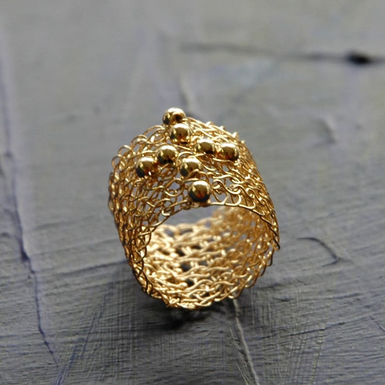 May include: A gold ring crafted from fine wire mesh, adorned with small gold beads.