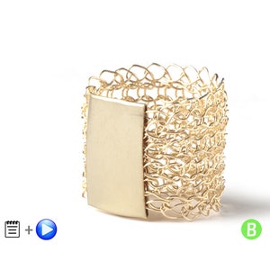 May include: A gold ring with a woven chain design and a flat, rectangular piece of metal on the side.