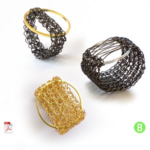 May include: Three wire rings, one gold, one silver, and one black, are woven into intricate patterns. The rings are displayed on a white surface.