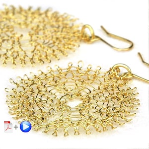 May include: Close-up of two gold-colored, circular earrings. The earrings have an intricate, open-weave design, with a series of small loops around the outer edge. The earring hooks are visible. The earrings are likely made of metal and are designed to be worn as jewelry.