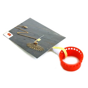 May include: A gold necklace with a delicate, intricate pendant in the shape of a fan. The necklace is displayed on a gray background with a red and white tag.