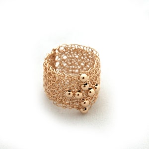 May include: A gold ring with a delicate, woven design and a cluster of small gold beads.