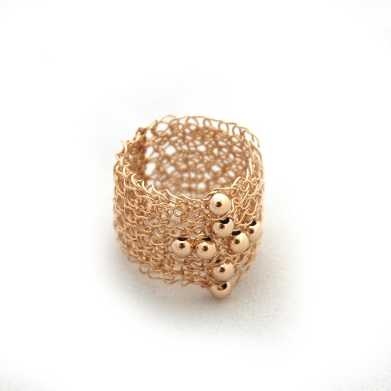 May include: A gold ring with a delicate, woven design and a cluster of small gold beads.