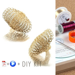 Könnte beinhalten: Zwei goldene Drahtgeflechtringe, einer ist oval flach und der andere ist konisch gekrümmt. Die Ringe werden auf weißem Hintergrund gezeigt. Das Bild zeigt auch ein DIY-Kit mit Draht, einer Spule Draht, einer CD und einer Nadel.