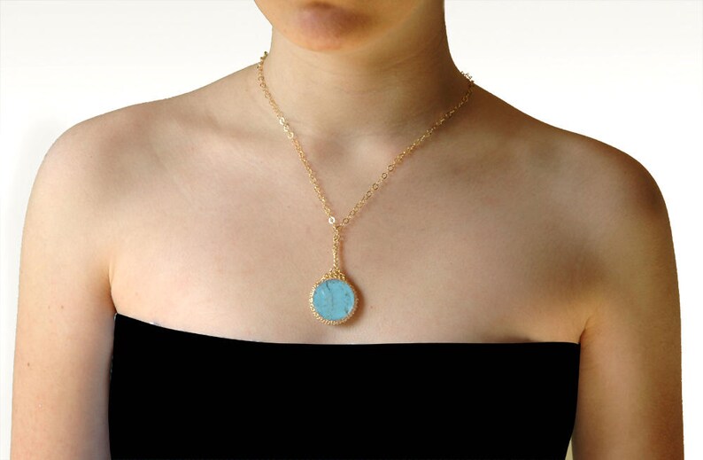 May include: A gold chain necklace with a round blue stone pendant.