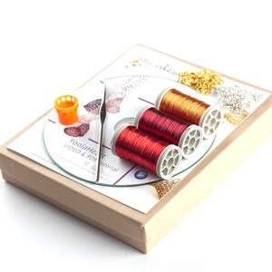 May include: A craft kit with three spools of copper wire in red and gold colors, a small orange plastic spool holder, and a CD with a printed label that says "YoolaHeart Tutorial VIDEO & PDF".