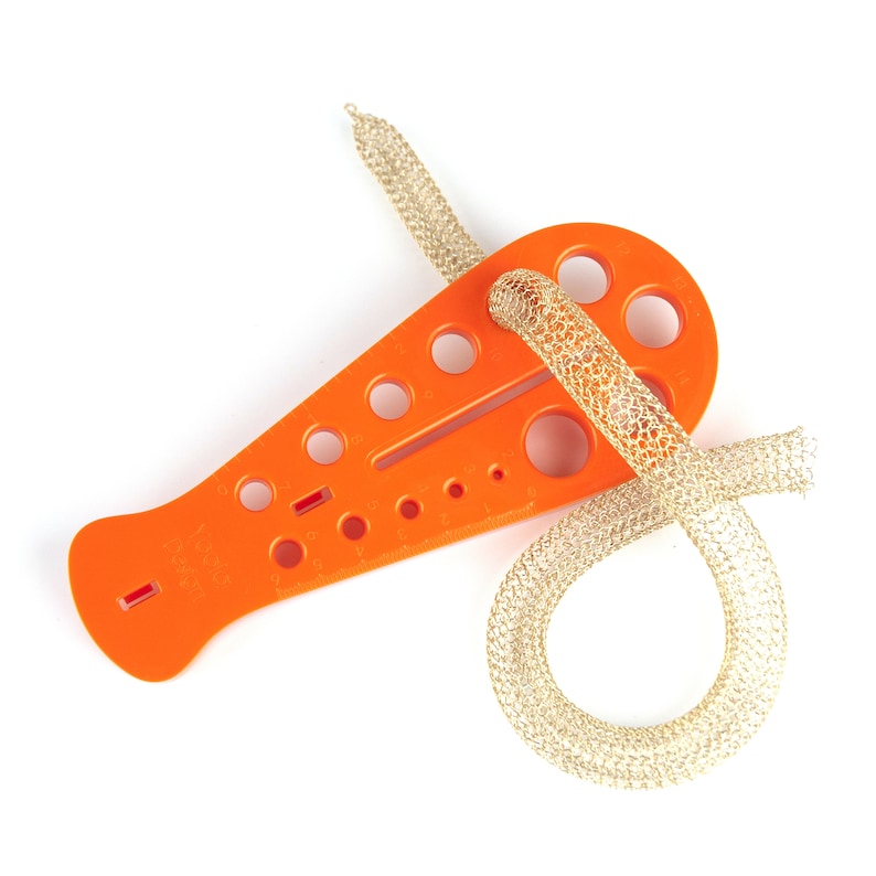 May include: Orange plastic tool with multiple sized holes for measuring and working with cord. A gold cord is wrapped around the tool.