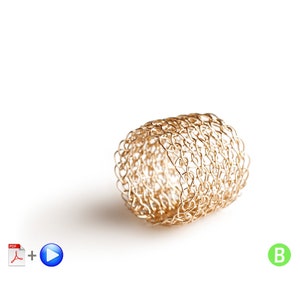 Könnte beinhalten: Ein goldfarbener, gewebter Metallring, zylindrisch geformt, liegt auf weißem Hintergrund. Der Ring besteht aus miteinander verbundenen, kleinen Metallschlaufen, die ein strukturiertes, offenes Design bilden. Der Ring wirft einen Schatten.