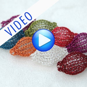May include: A close-up of six colorful wire-wrapped beads, each with a different color and texture. The beads are arranged in a row, with the play button icon in the center.