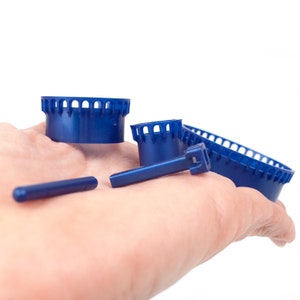 May include: Four blue plastic bobbins for a knitting machine. The bobbins are different sizes and shapes.