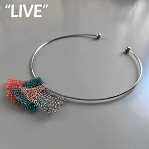 May include: A silver-toned choker necklace with a wire mesh pendant in red, green, copper, and silver. The word "LIVE" is in white text in the upper left corner. The necklace has a simple, modern design.