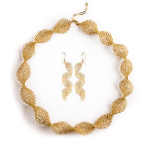 May include: A gold necklace and matching earrings made of delicate, interwoven metal. The necklace is a long, twisted chain with a clasp closure. The earrings are long and dangle, with a similar twisted design.
