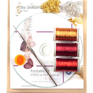 May include: A craft kit for making jewelry, featuring a CD, three spools of red wire, two piles of gold and silver chain, and a small orange bottle. The CD label reads "YoolaHeart VIDEO & PDF tutorial Y-la Design all rights reserved to Yael Falk aka La 2015 www.Yooladesign.com".