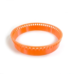 Könnte beinhalten: Orangefarbener Kunststoff-Strickring mit einer strukturierten Oberfläche und einer Reihe von Löchern am Rand.