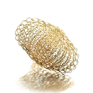 May include: A gold-colored metal mesh sculpture in the shape of an oval. The sculpture is made of many small, interconnected loops of wire.