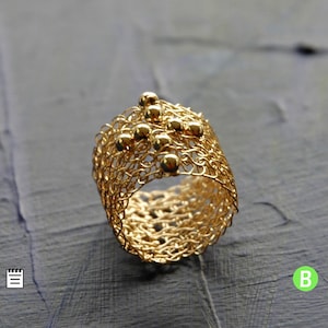 May include: A gold ring crafted from fine wire mesh, featuring small gold beads scattered across the design.