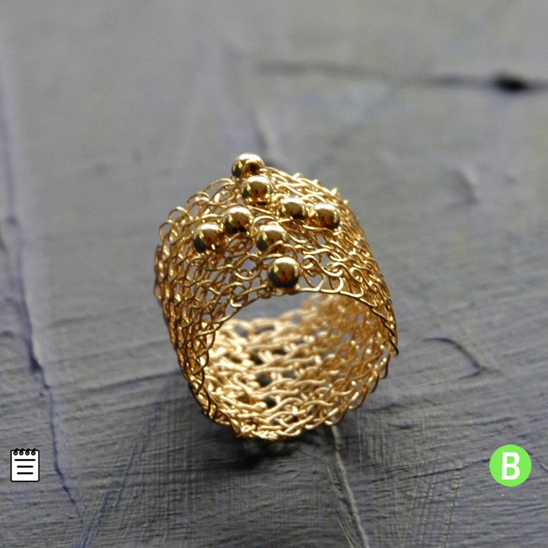 May include: A gold ring crafted from fine wire mesh, featuring small gold beads scattered across the design.