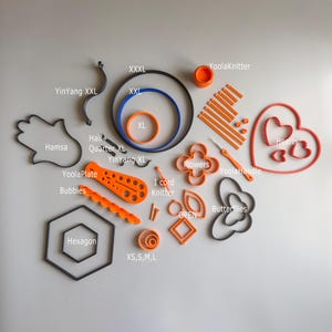 May include: An assortment of orange and black craft tools and shapes, including circles, flowers, hearts, and a hexagon. Text labels include "YoolaKnitter", "Hamsa", and "Hexagon".