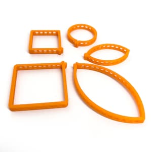 Puede incluir: Conjunto de cinco cortadores de galletas de plástico naranja en diferentes formas: un círculo, dos hojas y dos cuadrados.