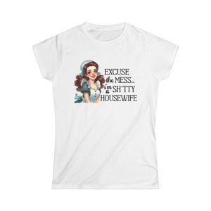May include: White t-shirt featuring a cartoon illustration of a woman in a maid outfit with the text "EXCUSE the MESS... i'm a SH*TTY HOUSEWIFE". The woman has brown hair and is wearing a blue and white uniform.