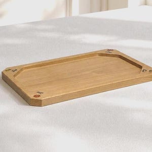 Può includere: Un vassoio rettangolare in legno con finitura marrone chiaro. Il vassoio ha un bordo rialzato e decorazioni floreali decorative ad ogni angolo. Progettato per servire cibo o esporre oggetti.