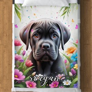May include: A black dog with a brindle pattern, with a name "reagan" written in white cursive on a floral background.