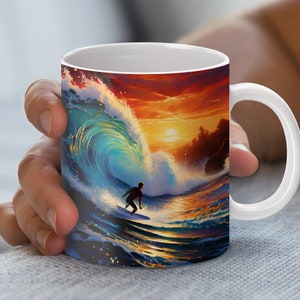 May include: White ceramic mug featuring a vibrant illustration of a surfer riding a wave at sunset. The artwork showcases a dynamic ocean scene with a silhouetted surfer, a large breaking wave, and a colorful sky.
